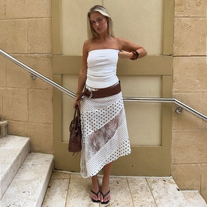 Detail of summer polka dot lace skirt paired with white crop top and brown leather belt