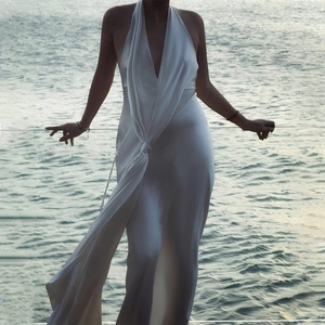 Detail of white satin halter dress featuring a deep V-neck and high leg slit design