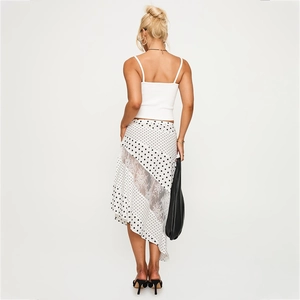 Detail of high-waist white polka dot skirt with sheer lace stitching and asymmetric cut
