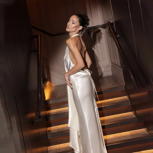 Detail of pearl white satin evening dress featuring a halter neck and open back design