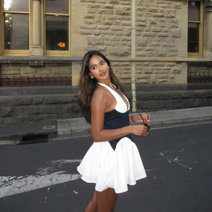 Chic halter neck mini dress with navy blue bodice and white pleated skirt for summer