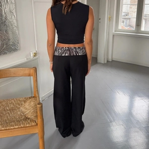 Détail arrière du pantalon noir taille haute pour femme avec ceinture à imprimé zèbre