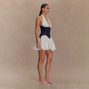 Side view of backless halter mini dress featuring a blue denim waist corset and white pleats