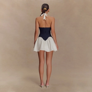 Back view of a backless halter mini dress featuring a blue denim corset and white A-line skirt
