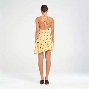Back view of yellow polka dot halter dress featuring an open back and irregular hemline