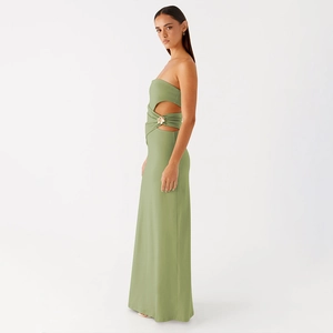 Détail d'une robe longue vert sauge avec découpe latérale et boucle florale dorée