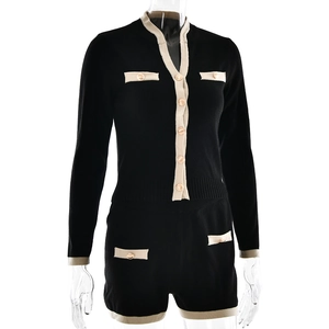 Detail of knit cardigan set featuring gold buttons and beige contrast trim on black fabric