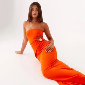 Détail de robe longue bustier orange vif avec découpe latérale et accessoire fleur dorée