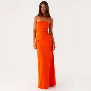 Détail d'une robe bustier orange vif avec découpe à la taille et fleur dorée chic