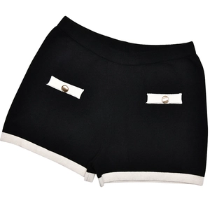 Detail of knit shorts featuring contrast white trim and elegant gold decorative buttons