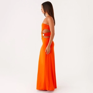 Détail de la robe longue bustier orange avec découpe à la taille et boucle florale argentée