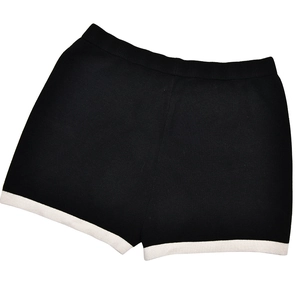 Detail view of black knitted shorts with white contrast piping and elastic ribbed waistband