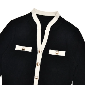 Detail of black tweed knit cardigan with contrast white trim and gold buttons