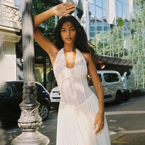 Detail of white halter neck maxi dress with pleated skirt and waist-defining cut