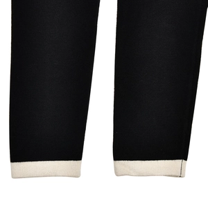 Detail of black knit cardigan sleeve with ivory ribbed cuffs showing texture and contrast