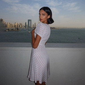 Close-up of a white V-neck mini dress with red polka dots and puff sleeves for summer