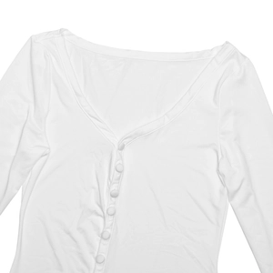 Détail du décolleté en V profond et des boutons recouverts de tissu sur le haut blanc