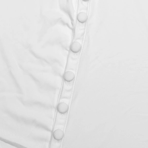 Gros plan des boutons recouverts de tissu sur la patte d'une robe longue blanche