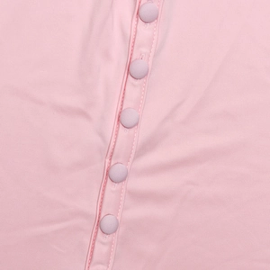 Détail d'une robe en maille rose avec cinq boutons recouverts de tissu et texture