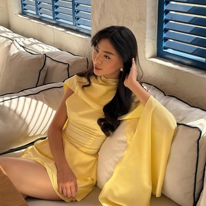 Détail d'une robe élégante en satin jaune avec manches cape et col montant chic