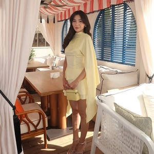 Ensemble élégant en satin jaune pâle avec haut cape et mini-jupe sur une terrasse