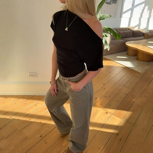 Maglia nera a pois con spalla scoperta e pantaloni larghi per un look alla moda