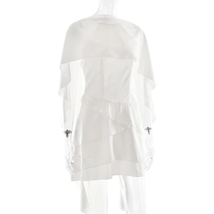 Détail de l'épaule cape blanche et de l'ourlet à volants superposés de la robe courte