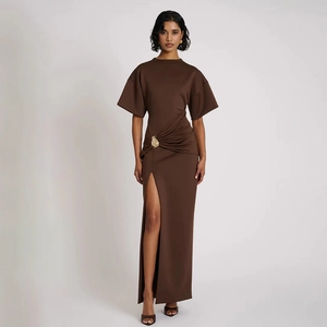 Dettaglio di elegante abito lungo marrone scuro con drappeggio, spacco e fibbia dorata