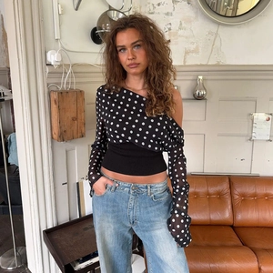 Detailed view of polka dot chiffon top with one-shoulder design and ribbed waist