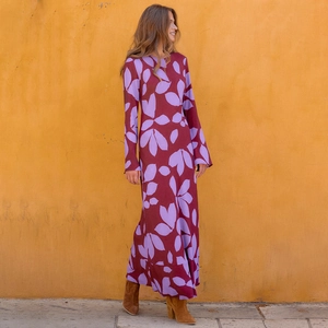 Détail d'une robe longue bohème à manches longues avec imprimé feuilles sur fond bordeaux