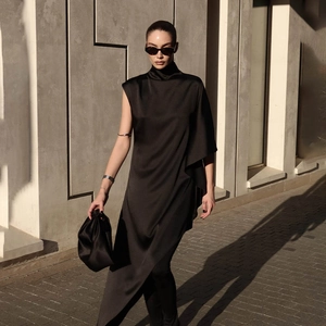 Détail de la robe en satin noir à col montant avec drapé asymétrique brillant