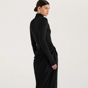 Détail de robe noire moulante à col montant avec design plissé élégant et manches