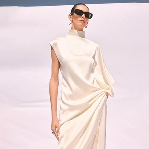 Détail d'une robe en satin crème sans manches avec col montant et texture drapée élégante