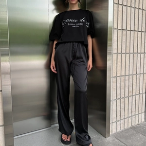 Detail der hoch taillierten schwarzen Satinhose mit Kordelzug und bedrucktem T-Shirt