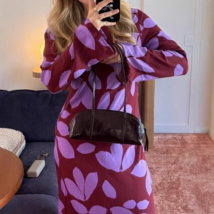 Détail d'une robe vintage à imprimé floral avec un sac à main en cuir verni brillant