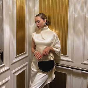 Détails de la robe en satin crème à col haut avec un sac à main à poignée en strass