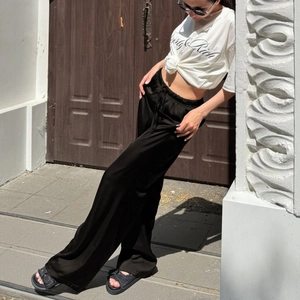 Detail einer schwarzen Satin-Hose mit hohem Bund und Kordelzug an einem Street-Style-Model
