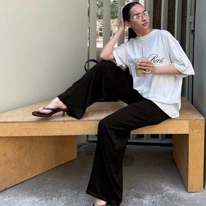 Outdoor-Aufnahme einer Frau in weißem T-Shirt und schwarzer High-Waist-Hose mit weitem Bein