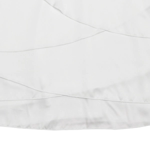 Détail macro d'une robe en satin blanc montrant l'ourlet à volants et coutures fines