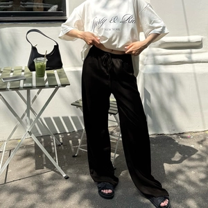 Detailaufnahme einer schwarzen High-Waist-Hose mit weitem Bein, Kordelzug und weichem Fall