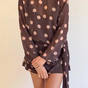 Détail d'une robe marron à pois en mousseline avec ceinture et texture semi-transparente