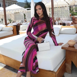 Detail of colorful striped long sleeve dress with white quilted handbag on resort patio