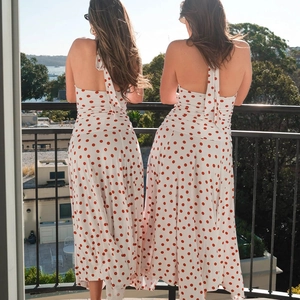 Back view of a white polka dot halter dress featuring an open back and neck ties outdoors