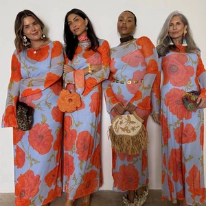 Detail of sheer long sleeve maxi dress featuring vibrant orange floral poppy print patterns
