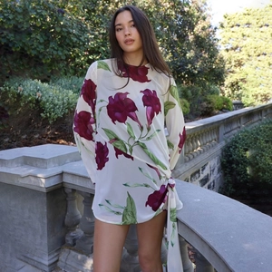 Détail d'une robe en mousseline blanche avec imprimé floral violet et nœud sur le côté