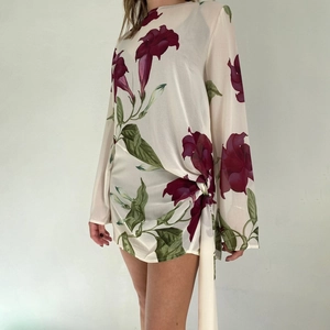 Détail d'une mini robe en mousseline avec nœud à la taille et motifs floraux violets