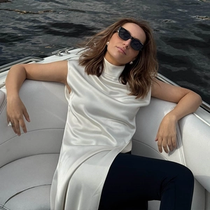Dettaglio del top senza maniche in raso bianco a collo alto indossato su uno yacht