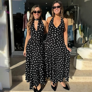 Detail of a black halter neck dress with white polka dots and asymmetric ruffled hemline