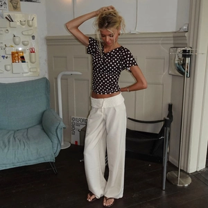 Detail shot of black polka dot slim fit t-shirt paired with white high waist wide leg pants