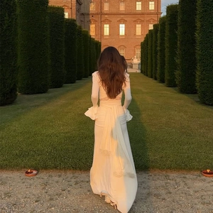 Detail view of the elegant cape drape back and ruffled flare sleeves on this white gown